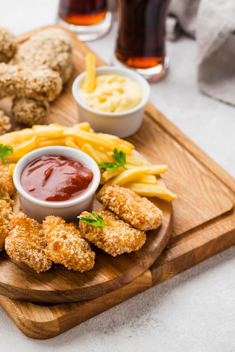 Tábua com petiscos: nuggets, batatas fritas e molhos.